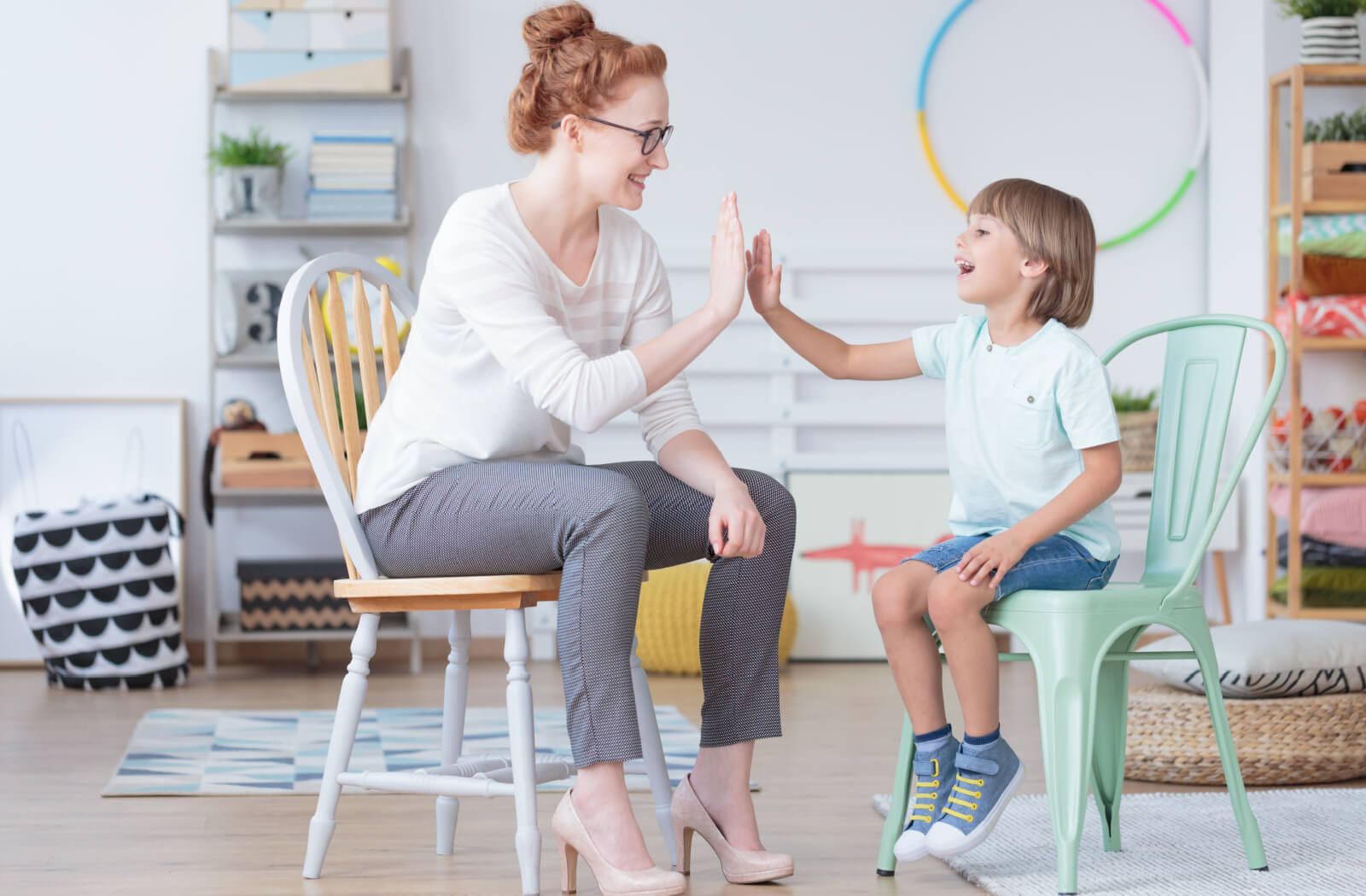 Young boy and pediatric optometrist having fun during conversation in colorful room with toys