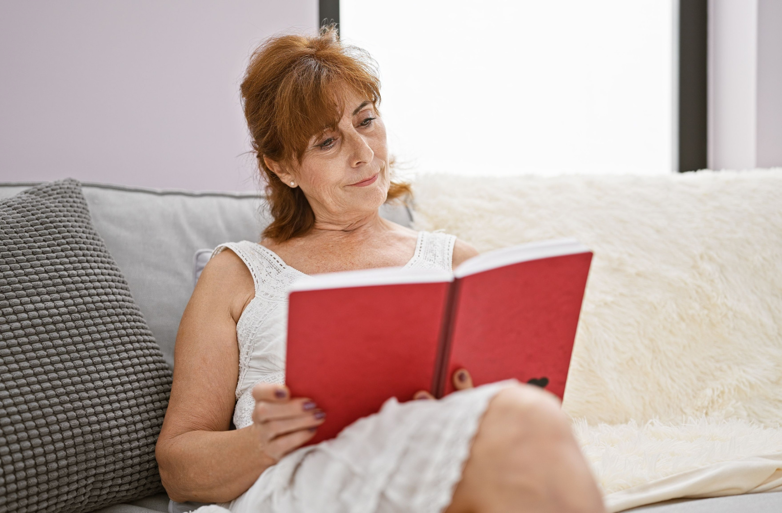 A woman reading a book in a brightly lit room.