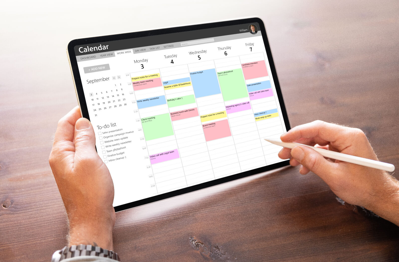 Close-up of a person holding a tablet and viewing a digital calendar on it while using a digital pen