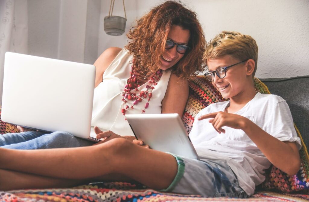 Young boy sitting on the couch with his mother using a tablet to help him read smaller text.