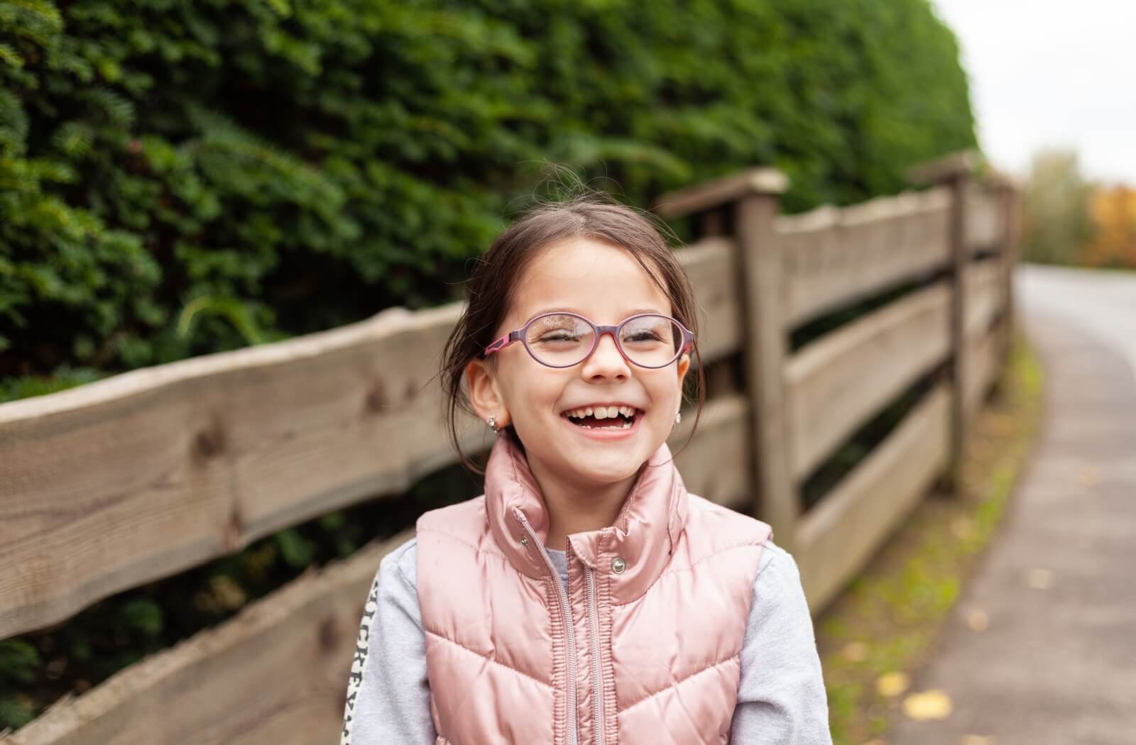 Happy young girl in glasses standing outside.